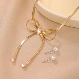 Elegantes Schmuckset mit goldener Schleife, Perlenkette und Ohrringen auf Seide