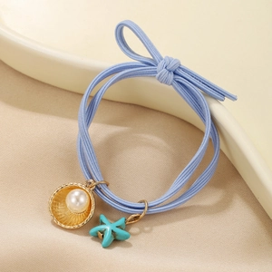 Blue ocean style hair tie with pearl shell and starfish charms on ceramic tray