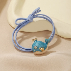 Close-up of blue whale enamel charm on elastic hair tie with light blue bow detail