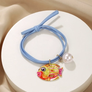 Close-up of blue elastic hair tie with enamel fish pendant and white faux pearl detail