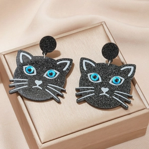 Cute black cat stud earrings with blue eyes and glitter finish on a satin background