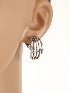 Detailed view of punk style silver skeleton hand clip earrings on a model ear