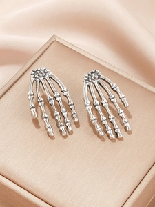 Nahaufnahme der Vintage Skeletthand-Ohrringe aus Silber auf Champagnerseide