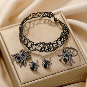 Gothic spider jewelry set including choker, earrings, and ring on gold silk background