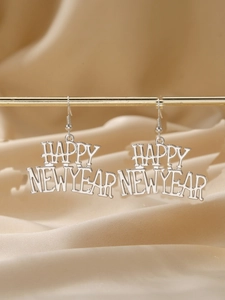 Gros plan de boucles d'oreilles argentées Happy New Year sur un support de présentation doré