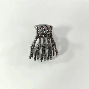 Dettaglio della molletta per capelli a forma di mano scheletrica in metallo scuro