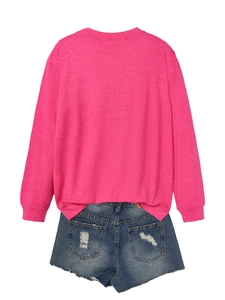 Flat lay of pink long-sleeve top with STRONGER lettering and frayed denim shorts