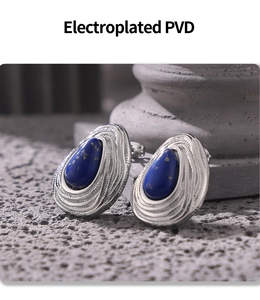 Macro shot of PVD electroplated blue gemstone stud earrings on a textured stone base