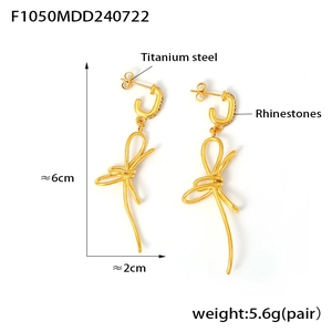 Macro detail of titanium steel bow earrings with rhinestones and 18K gold plating