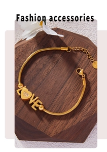 Detail of gold LOVE bracelet with heart-shaped crystal inlay and snake chain closure