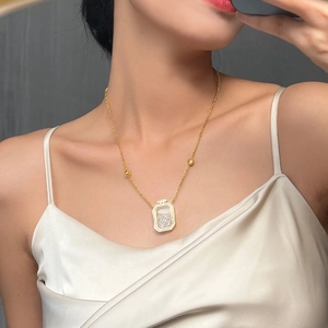 Elegant gold perfume bottle necklace with shimmering rhinestones on a silk dress