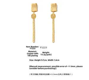Macro view of 18k gold plated copper earrings with coin pendant and long tassel chain