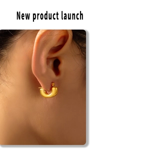 Close-up of polished gold plated U-shaped huggie earrings worn by a model