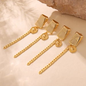 Gold plated portrait coin earrings with long tassels on a stone textured background