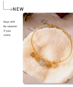 Detail of gold bead bracelet with heart charms and a sparkling zircon center on coral base