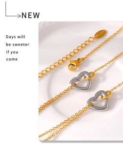 Detailed macro of gold lobster clasp and extension chain with hollow heart charms