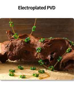 Detail of PVD electroplated gold chain with green glass flower beads on wooden stand