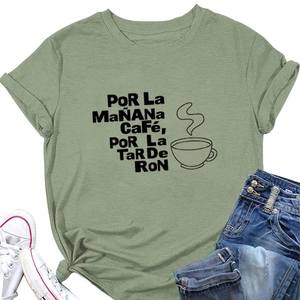 Détail du t-shirt vert sauge avec imprimé Por La Mañana Café, jean bleu et baskets blanches