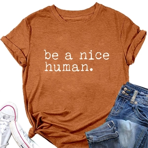 Détail d'un t-shirt orange caramel avec imprimé be a nice human et nœud à l'ourlet