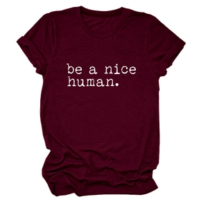 Gros plan du slogan 'be a nice human' sur un t-shirt bordeaux à col rond et manches courtes