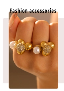 Detalle de anillo dorado con perlas blancas y bolas de strass brillantes en dedo de modelo