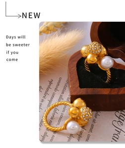 Detalle macro de anillos trenzados bañados en oro de 18k con perlas y diamantes