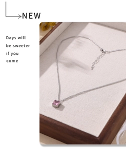 Detail eines quadratischen rosa Zirkon-Anhängers mit silberner Kette auf Holztablett