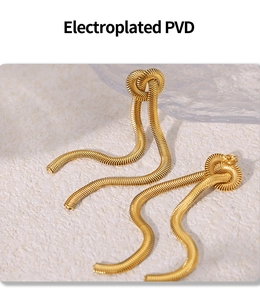 Detail of gold snake chain tassel earrings with electroplated PVD finish on stone background