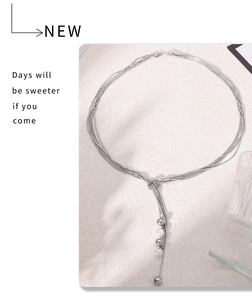 Detail of multi-layer snake chain necklace with faux pearl tassel and silver metallic beads