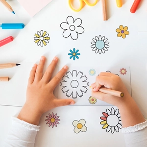 Flat lay of child coloring floral doodle wall stickers with markers and pencils