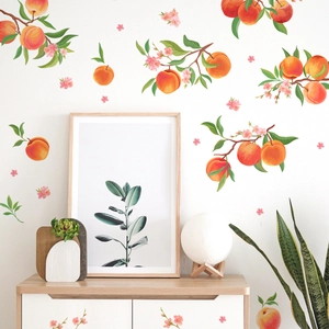 Peaches and floral wall decals on a white wall above a wooden cabinet in a home setting