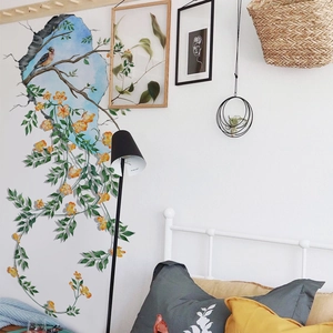 Lifestyle view of floral wall sticker with birds and green leaves on a bedroom white wall