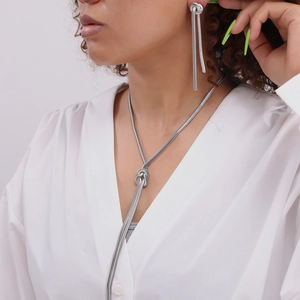 Silver snake chain jewelry set with knot design and long tassels on female model