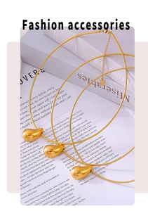 Détail de colliers multicouches dorés avec pendentifs larmes polis sur des livres blancs