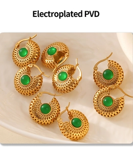 Détails macro des boucles d'oreilles dorées avec pierres vertes plaquées PVD