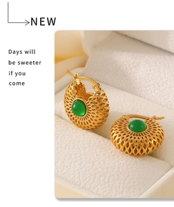 Détail de boucles d'oreilles vintage dorées avec verre vert et design ajouré chic