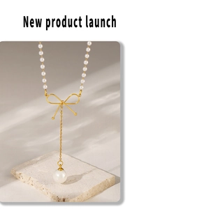 Détail d'un collier ras du cou en perles avec pendentif nœud doré sur fond de pierre