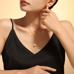 Ensemble collier et boucles d'oreilles nœud doré avec perles porté par un mannequin
