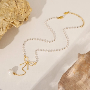 Collier ras de cou en perles avec noeud doré élégant sur fond de pierre naturelle