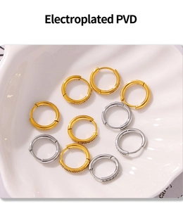 Macro view of PVD gold and silver hoop earrings with zircon in a shell tray