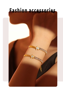Detail of gold titanium steel bracelet with pavé star charm and baguette cubic zirconia