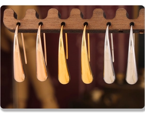 Detalle macro de pendientes de gota en oro, plata y oro rosa en un soporte de madera