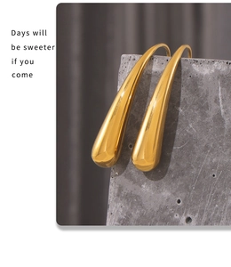 Detalle macro de pendientes de gota bañados en oro pulido en soporte de piedra