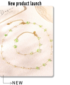 Détail du collier en acier doré avec des pierres irrégulières vertes et blanches
