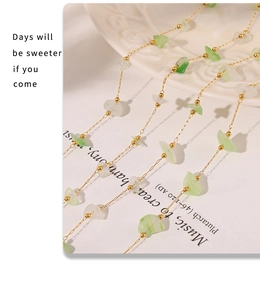 Détail d'une chaîne dorée style français avec perles en pierre naturelle verte et blanche