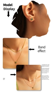 Detail of layered gold necklace set with green sunflower pendant and flat snake chain