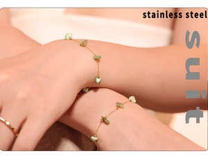 Detail of gold stainless steel necklace and bracelet set with green heart stone charms