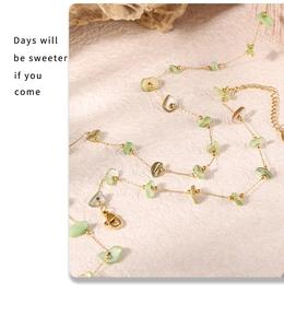 Macro detail of French vintage gold necklace with green stones on a white stone background