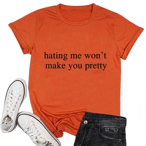 Close-up of bright orange crewneck T-shirt with 'hating me won't make you pretty' slogan