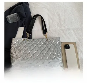 Detail show of silver quilted tote bag with black leather handles and gold chain accents